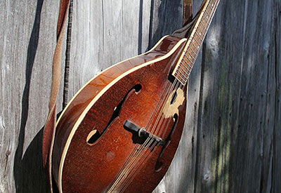 old mandolin hangs on barn wall