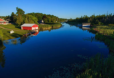calm river on summer day with red boat house 